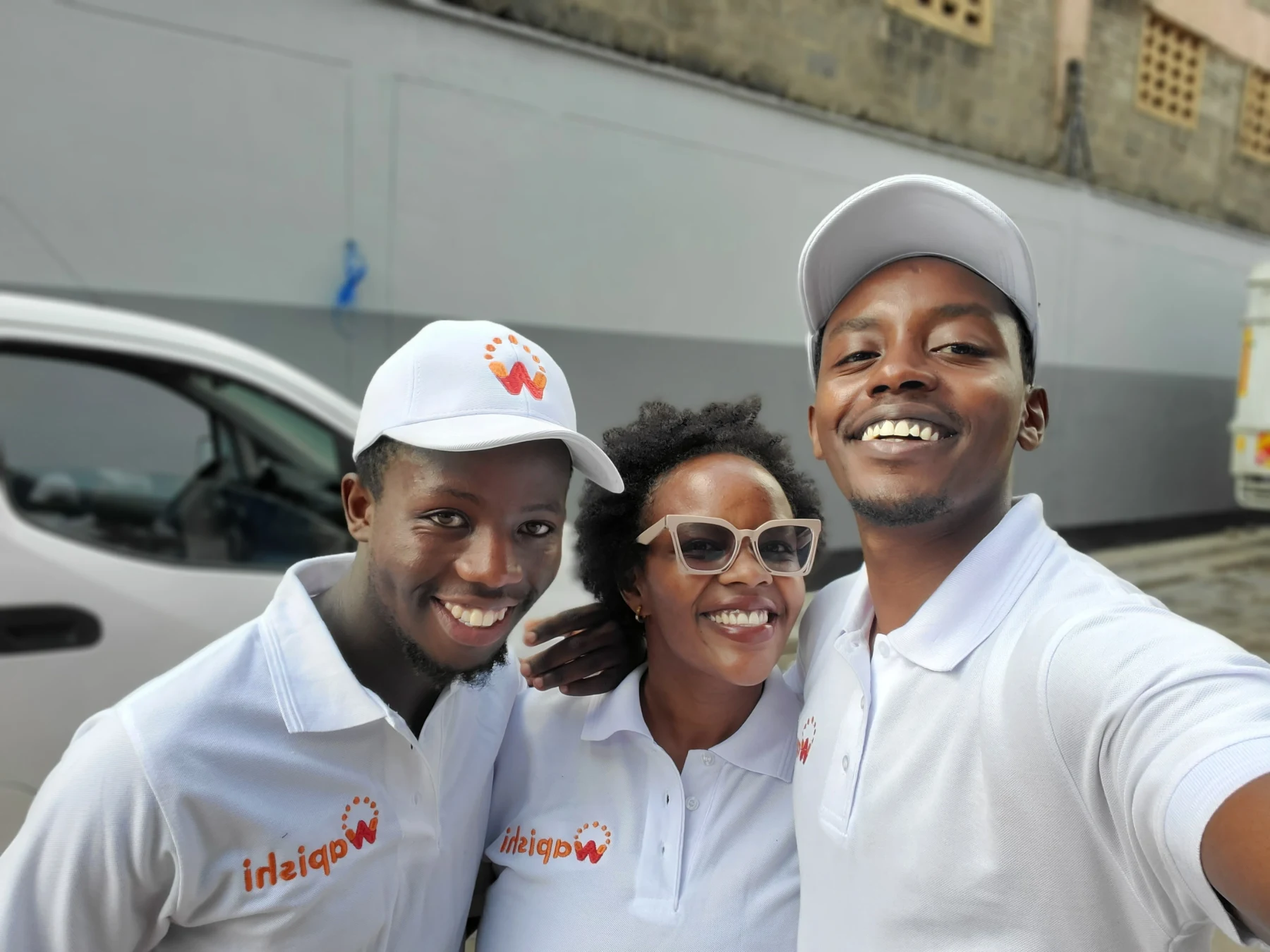 The three-person Wapishi team smiling together in white branded shirts